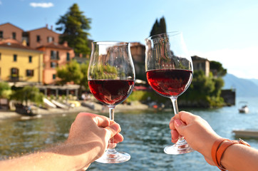 Two wineglasses in the hands. Varenna town at the lake Como, Ita