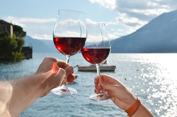 Two wineglasses in the hands. Varenna town at the lake Como, Ita