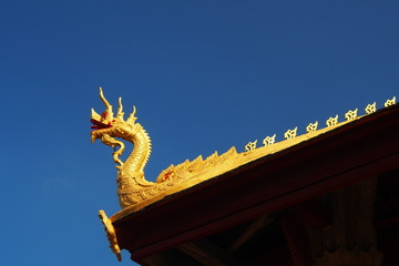 Fototapeta na wymiar Naga structure decoration on gable of Laos temple in blue sky