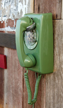 green retro telephone on wooden wall