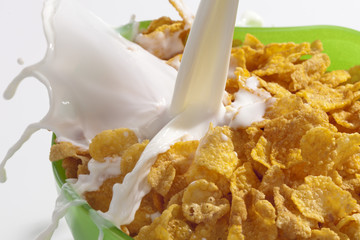 Cornflakes im grünen Glasschälchen und Milchstrahl