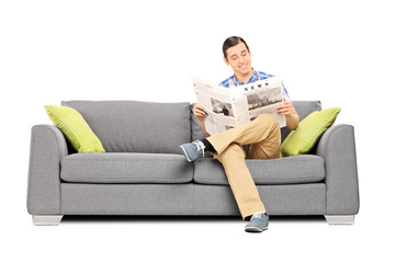 Peaceful young man reading the news seated on sofa