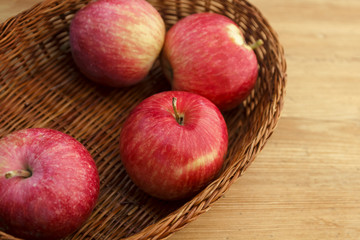 Red apples and basket on wooden background