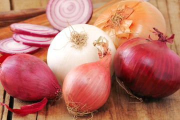 Different types of onion on wooden table