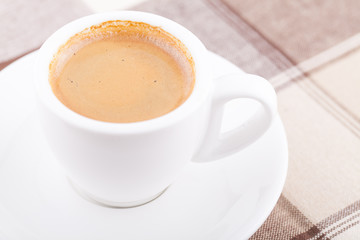 White cup of coffee on tablecloth