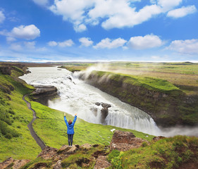 Delighted woman tourist on the shore of the waterfall. Gyullfoss