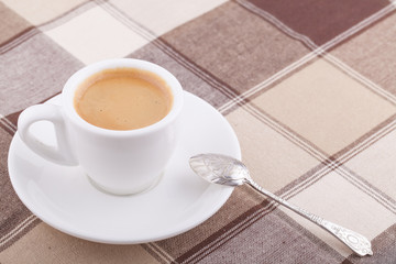 White cup of coffee on tablecloth