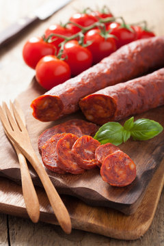 spanish chorizo sausage with basil on chopping board