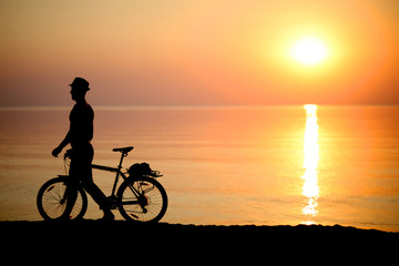 Fototapeta na wymiar Cyclist on background of sunset, sport and rest concept