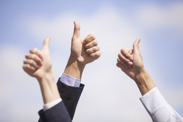 Close-up of business team holding their thumbs up.
