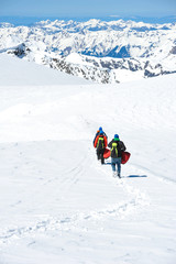 Naklejka na ściany i meble A group of mountain hiker walking on the snow into the mountain