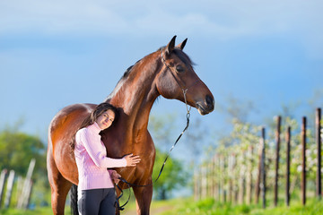 Young beautiful girl standing with a horse in garden