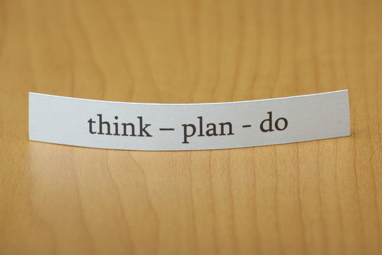 Think Plan Do on a slip of paper on a wooden desktop