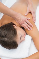 Fototapeta na wymiar Attractive woman receiving shoulder massage at spa center