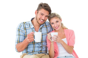 Attractive young couple sitting holding mugs