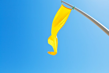 Beach safety yellow flag with blue sky