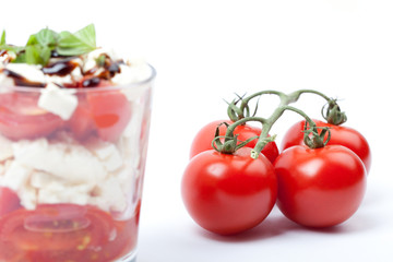 Cocktail Tomaten mit Schafskäse im Glas vor weißem Hintergrund