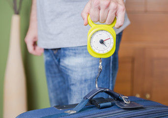 Man checking luggage weight with steelyard balance