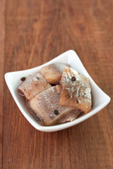 herring in white dish on brown background