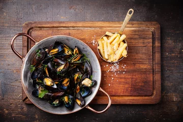 Keuken foto achterwand Mussels in copper cooking dish and french fries on dark wooden b © Natalia Lisovskaya