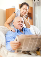  senior guy with newspaper and mature wife