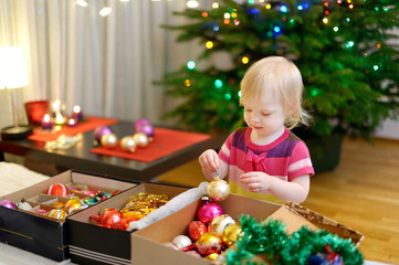 Fototapeta na wymiar Adorable little girl decorating a Christmas tree