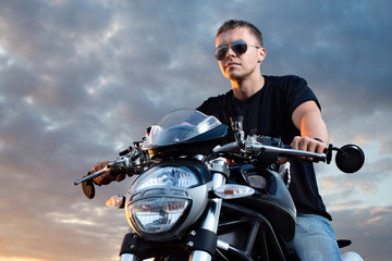 Fototapeta na wymiar Romantic portrait handsome biker man on a sunset near lake