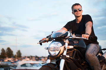 Fototapeta na wymiar Romantic portrait handsome biker man on a sunset near lake