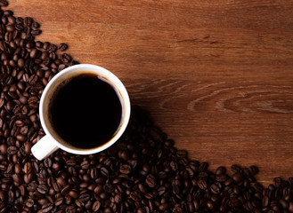 cup of black coffee with roasted coffe beans on the desk