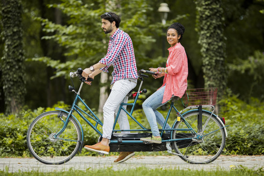 Young couple riding on the tandem bicycle