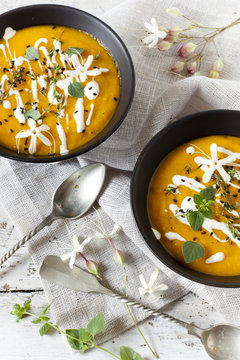 ream of pumpkin and carrot soup on bowls with sour cream