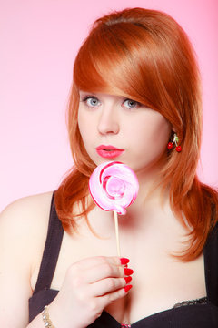 young woman holding candy. Redhair girl eating ollipop