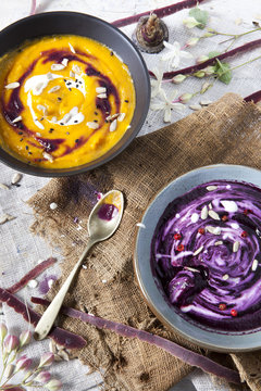 cream of pumpkin and purple carrot soup on bowls with sour cream