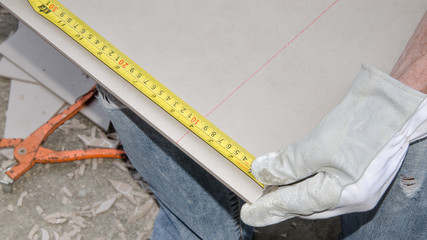 Tiler measuring tile before cutting