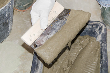 Tiler taking tile adhesive with a notched trowel