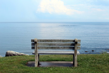 cement and wood bench on a cliff overlooking a calm sea