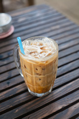 A glass of milk-coffee on wood table