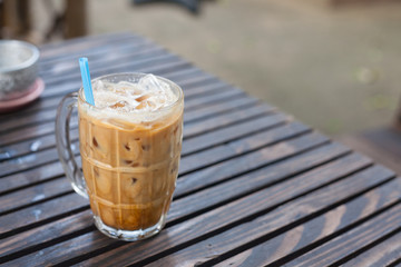 A glass of milk-coffee on wood table