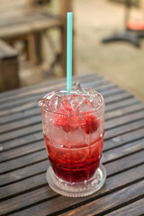 A glass of strawberry italian soda on wood board
