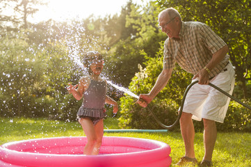 Grandparent and grandkid playing with hose