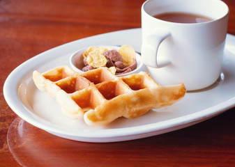 Cereal and waffle placed next to a tea cup