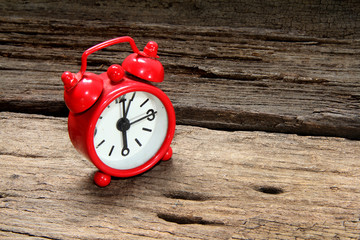 Red alarm clock on wooden background.