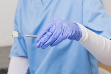 Dentist in blue scrubs holding angled mirror