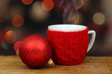 Christmas ball and hot drink in a cup in front of sparkle lights