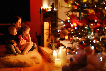 Young mother and her daughters by a fireplace