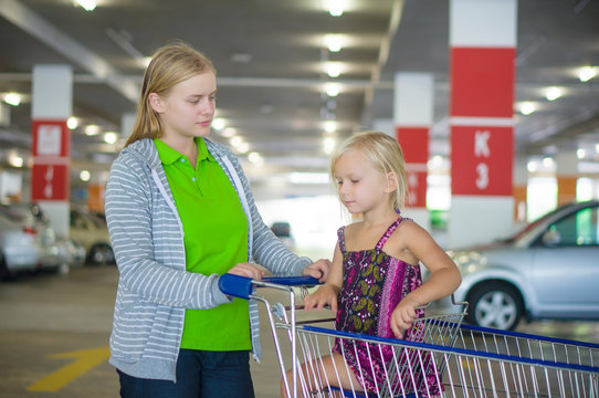 Young mother and adorable daughter in shopping cart on undergrou