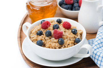 oat porridge with fresh berries and honey, close-up, isolated