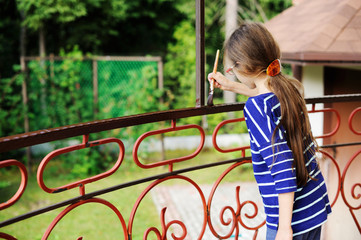 Smiling little girl  painting fence