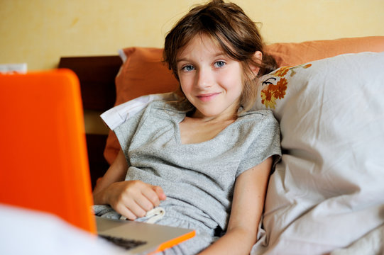 Smiling young preteen in bed using a laptop