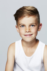 Portrait of young boy in vest, studio.